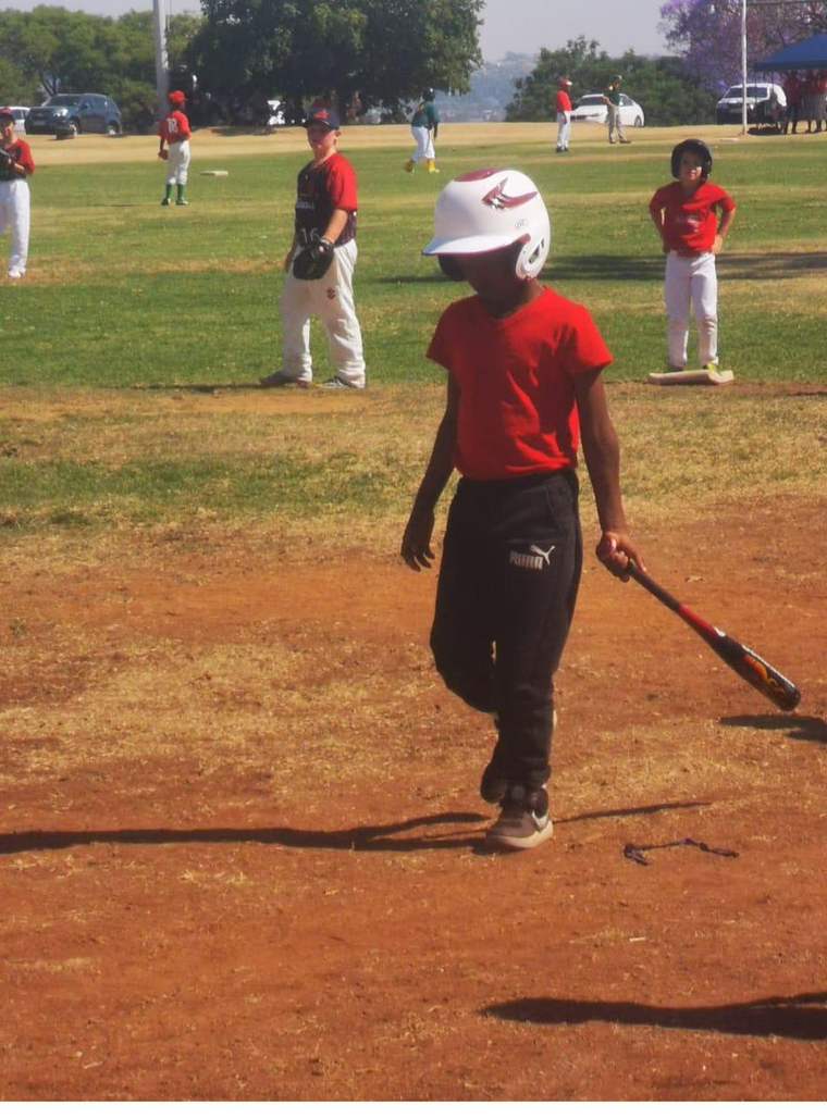 Young Tinashe walking to the plate dragging his bat